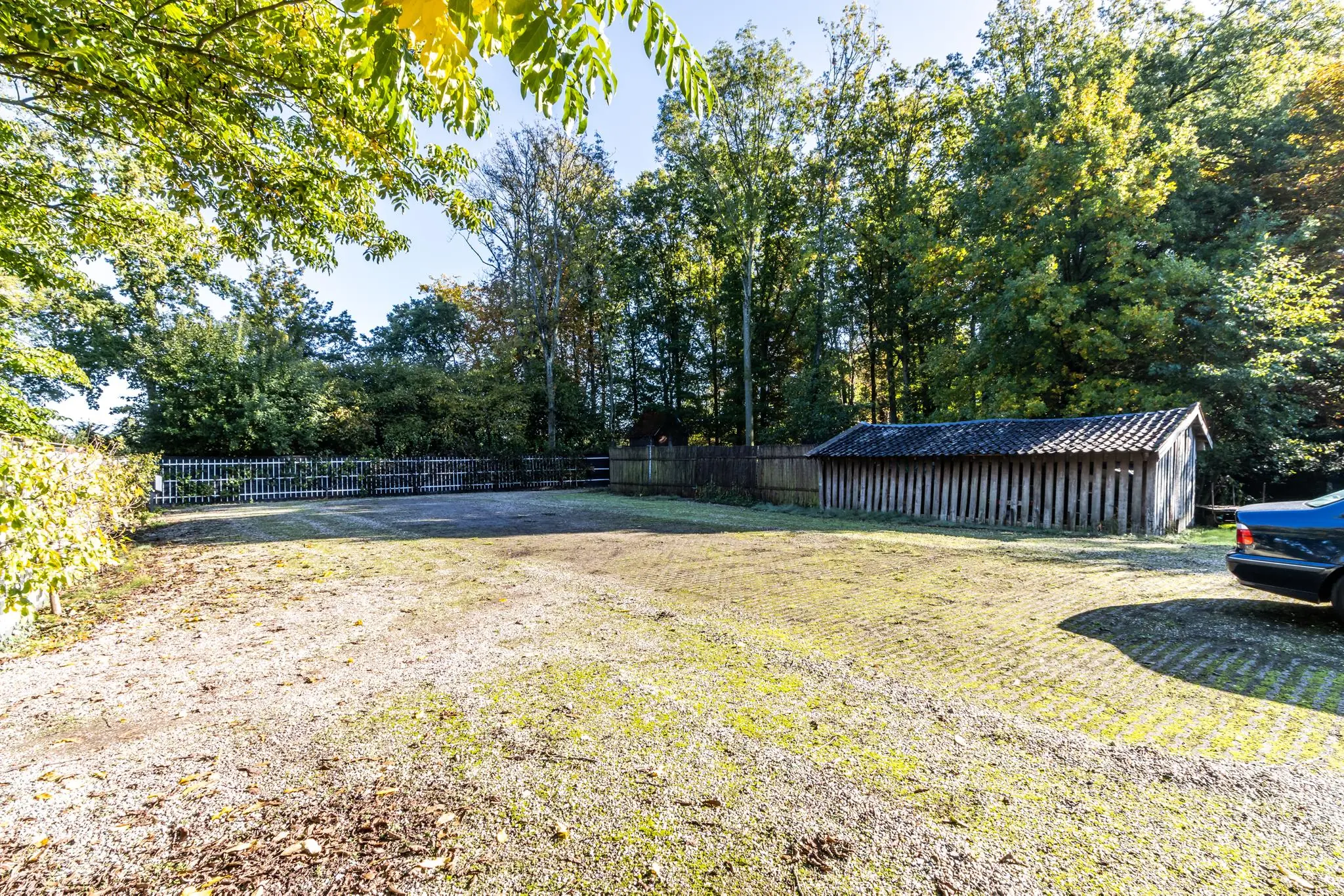 Open parkeerterrein aan de Langbroekerdijk met een houten schuurtje en omringende bomen.